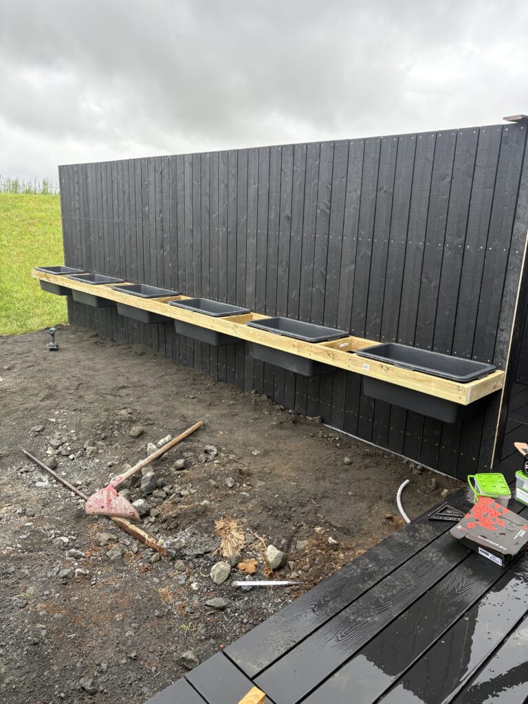 Skjólveggur sem búið er að klæða beggja vegna og smíða á blómaker rétt fyrir utan Selfoss